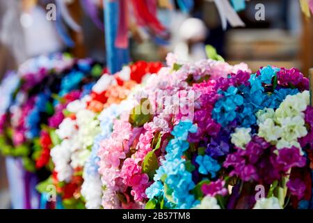 Close up of colorful artifical flowers bunched together hanging on a rack with shallow depth of field Stock Photo