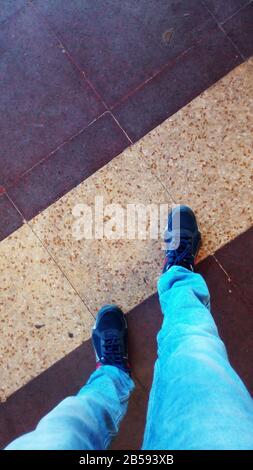 Man standing or walking in a mzaic floor wearing jeans and shoe Stock Photo