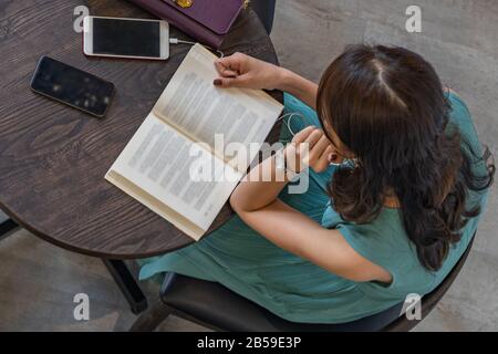 Top view photo of woman reading book at coffee table Stock Photo