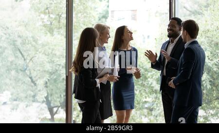 Smiling diverse colleagues have fun talking in office Stock Photo