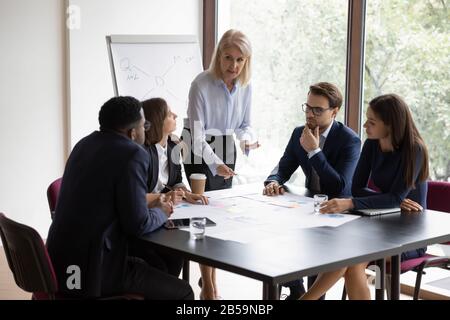 Focused female boss brainstorm with diverse colleagues at briefing Stock Photo