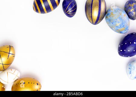 Happy Easter. Frame for text made of easter eggs trendy colored classic blue, white and golden on white. Minimal style, top view, flatlay, copy space. Stock Photo