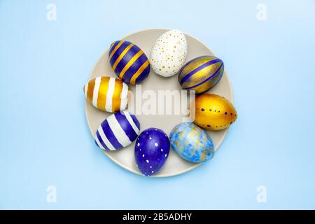 Happy Easter. Plate with easter eggs trendy colored classic blue, white and golden on blue background. Minimal style. Flat lay, top view Stock Photo