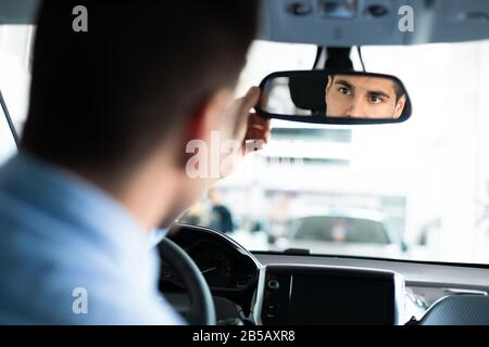 Guy Checking Mirrors Sitting In Driver's Seat In Dealership Store Stock Photo