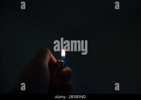 Fire in a hand in a dark room. Sad concept, memory of a man. Lighter with copy space Stock Photo