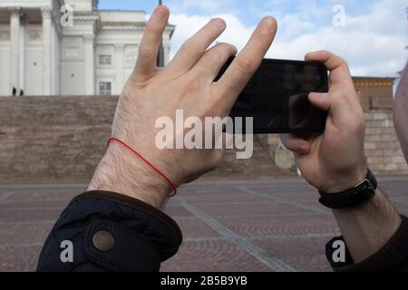 Tourist takes a photo on his phone close-up. Smartphone in hands with outdoor background. Black display Stock Photo