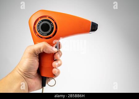 Vintage orange hair dryer on white background with rolled cable buttom. Stock Photo