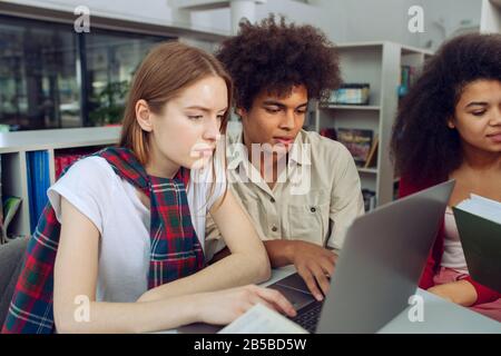 University students are studying in a library together. Concept of teamwork and preparation Stock Photo