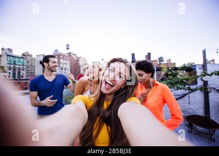 Group of friends spending time together on a rooftop in New york city, lifestyle concept with happy people Stock Photo