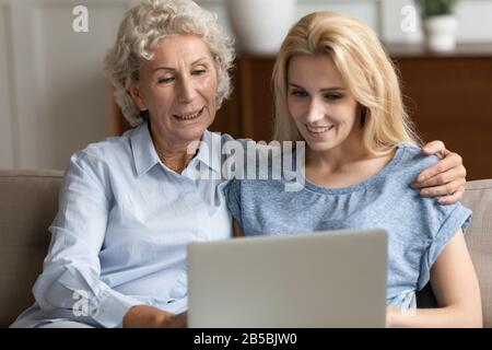 Happy senior mother and adult daughter using laptop Stock Photo