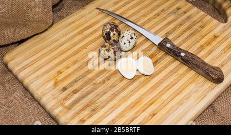 Hard boiled quail egg halves with egg shells on wooden board, photographed with natural light Stock Photo