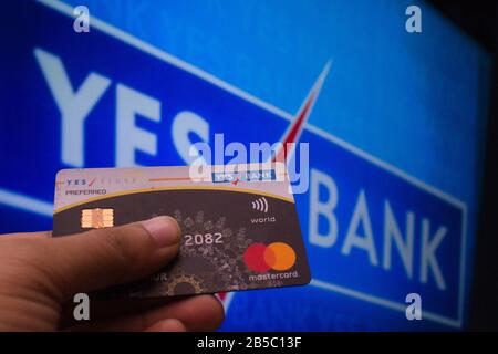 A person seen holding a credit card by Yes Bank infront of the yes bank board Stock Photo