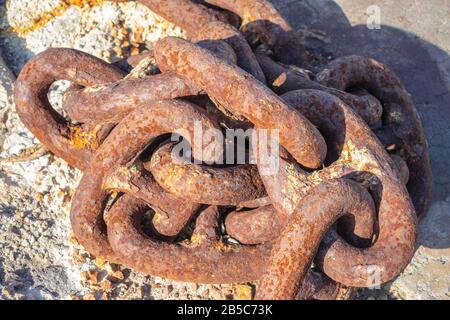 Old rusty steel chain on the harbour on a sunny day Stock Photo