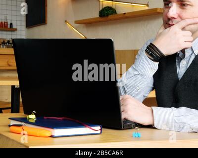 Young man is reading information in laptop in the cafe. Stock Photo