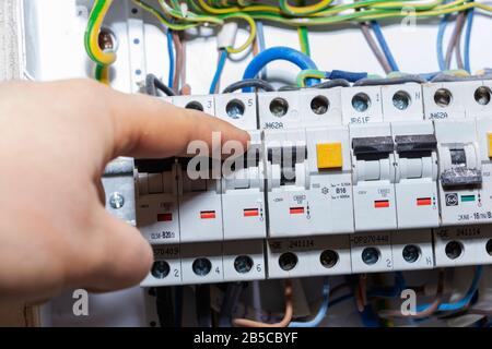 The hand points to a fuse in the power meter. The man disables the current fuses, the safety concept of the power suppression, and the protection of e Stock Photo