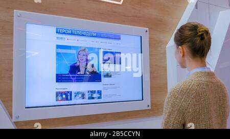 Woman watching TV news on interactive display wall Stock Photo