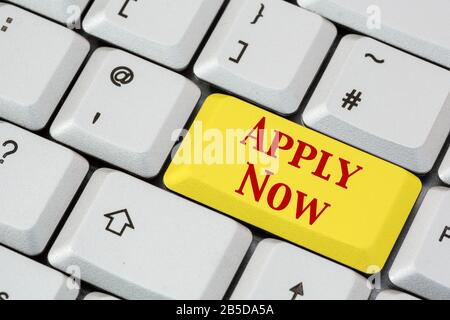 A keyboard with Apply Now written in red lettering on a yellow enter key. Job application career concept. England, UK, Britain Stock Photo