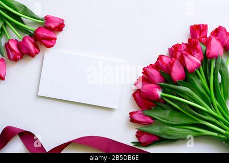 White Blank Card Near Tulip Bouquets And Ribbon. Congratulations and Celebration. International Women Day, Anniversary. Birthday. Date. Wedding Stock Photo