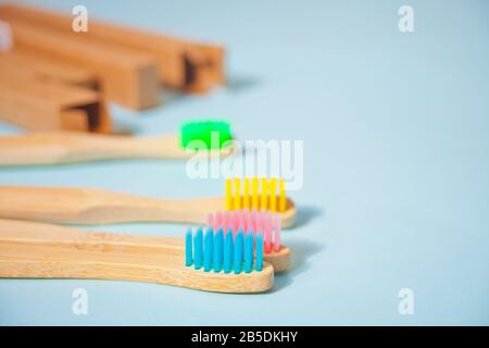 Four eco bamboo kid colorful toothbrushes on the blue background. Stock Photo