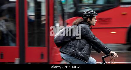 Belgrade, Serbia - September 24, 2019 : Young  man with a ponytail riding a bike  on a busy rainy day in motion blur Stock Photo