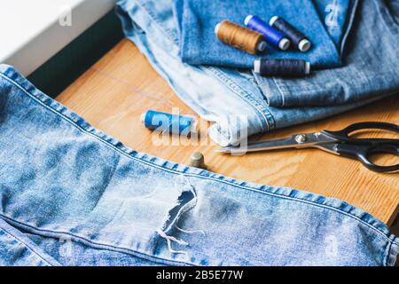 Handicraft, repair and tailoring. Sewing accessories threads close-up denim on a wooden table. Horizontal frame copy space Stock Photo