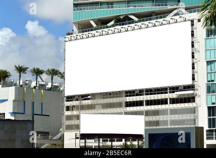 Large and small billboards on building side wall. Modern city, palm trees, blank ad space. Banner edge and grommets preserved for a more realistic loo Stock Photo