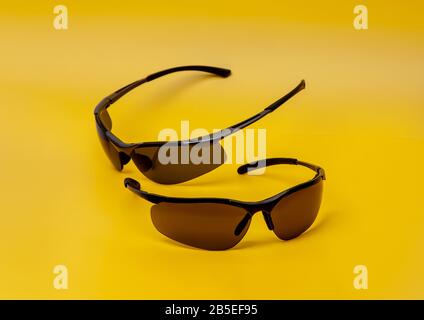 Modern safety goggles for athletes and workers. Stylish sports glasses on a colored background. Yellow background. Stock Photo