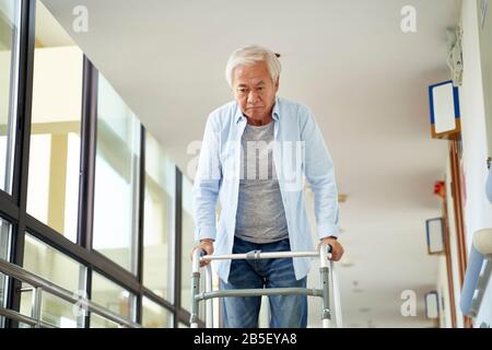 senior asian man walking using a walker in hallway of hospital or nursing home Stock Photo