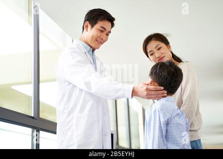 friendly young asian pediatrics doctor talking to mother and son in hospital hallway Stock Photo