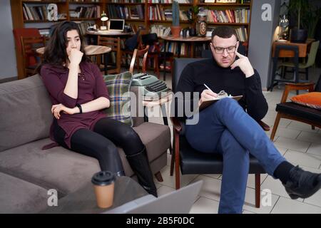 Female patient talking to her therapist who is making notes in home private office Stock Photo