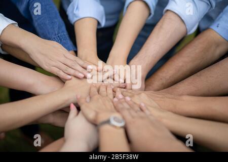 Close up to Asian people hold hand together in the middle of their group, friend with stack of hand showing the love and community of good friends. Stock Photo