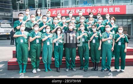 (200308) -- WUHAN, March 8, 2020 (Xinhua) -- Medical workers from Jiangsu Province pose for a group photo in front of a makeshift hospital in Wuhan, central China's Hubei Province, March 8, 2020. The makeshift hospital, converted from a sports venue, was announced close on Sunday. (Xinhua/Xiao Yijiu) Stock Photo