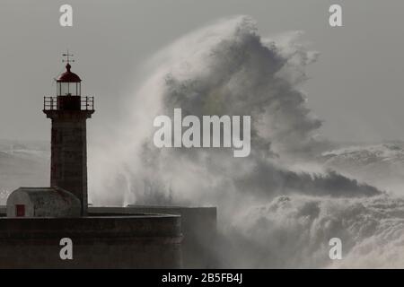 Big stormy wave splash. Old Douro river mouth lighthouse and pier, Oporto. Stock Photo