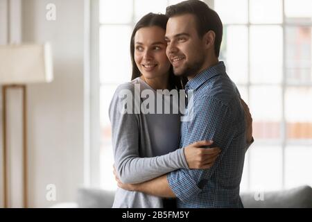 Loving affectionate married couple cuddling, looking away. Stock Photo