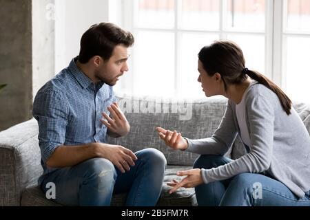 Stressed young married family couple arguing, blaming each other. Stock Photo