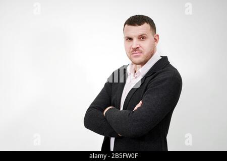 Portrait of an elegant young businessman standing with arms crossed over grey background Stock Photo
