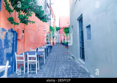 Cafe and restaurants at amazing narrow streets of popular destination on Crete island. Greece. Traditional architecture and colors of mediterranean ci Stock Photo