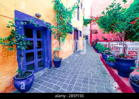 Cafe and restaurants at amazing narrow streets of popular destination on Crete island. Greece. Traditional architecture and colors of mediterranean ci Stock Photo