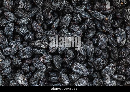 Black Raisin texture, popular dried fruit. Dried grapes. Red seedless raisins from grapes Stock Photo