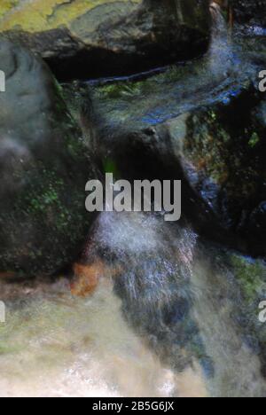 Small Stream Flows Over Dark Rocks Stock Photo