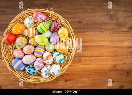 Easter eggs in various patterns and colors in a bird's nest placed on a wooden floor decorated in retro style. Stock Photo