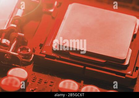 The central processor on the computer motherboard in red colors. PC repair, technician and industry support concept. Stock Photo