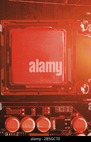 The central processor on the computer motherboard in red colors. PC repair, technician and industry support concept. Stock Photo