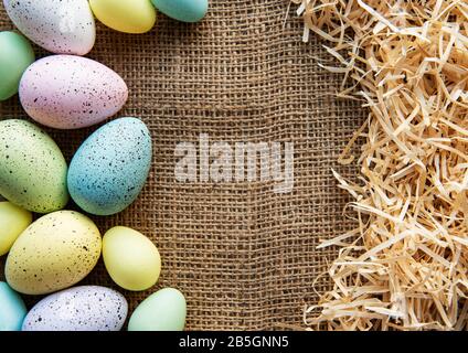 Easter eggs on a sackcloth and straw . Happy Easter  multicolored  easter eggs. Background with easter eggs. Flat lay, top view. Stock Photo