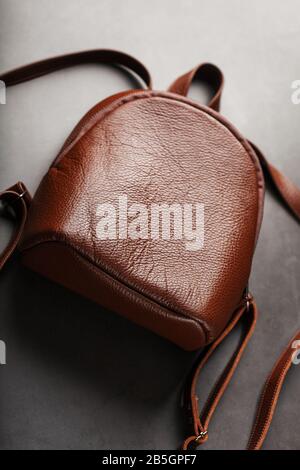 Brown backpack made of textured brown leather on a black stone background. Elegant golden brown women backpack with fashion and rivets. Genuine leathe Stock Photo
