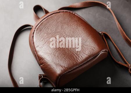 Brown backpack made of textured brown leather on a black stone background. Elegant golden brown women backpack with fashion and rivets. Genuine leathe Stock Photo