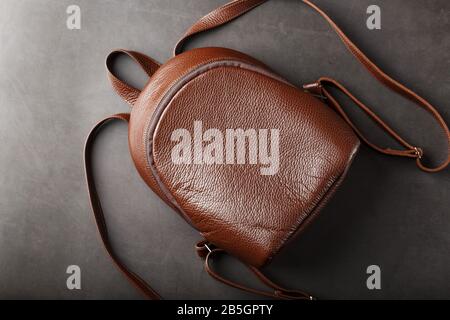 Brown backpack made of textured brown leather on a black stone background. Elegant golden brown women backpack with fashion and rivets. Genuine leathe Stock Photo