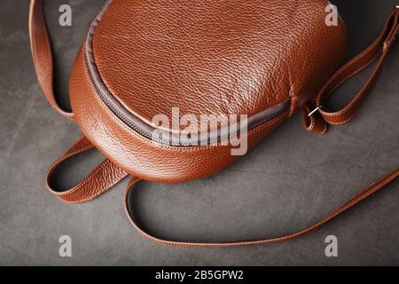 Brown backpack made of textured brown leather on a black stone background. Elegant golden brown women backpack with fashion and rivets. Genuine leathe Stock Photo
