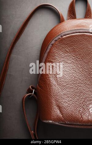 Brown backpack made of textured brown leather on a black stone background. Elegant golden brown women backpack with fashion and rivets. Genuine leathe Stock Photo