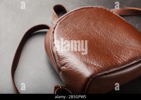Brown backpack made of textured brown leather on a black stone background. Elegant golden brown women backpack with fashion and rivets. Genuine leathe Stock Photo